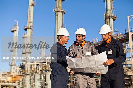 Travailleurs avec des plans à la raffinerie de pétrole
