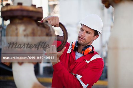 Worker adjusting gauge at chemical plant Worker adjusting gauge at chemical plant