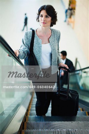 Businesswoman riding escalator