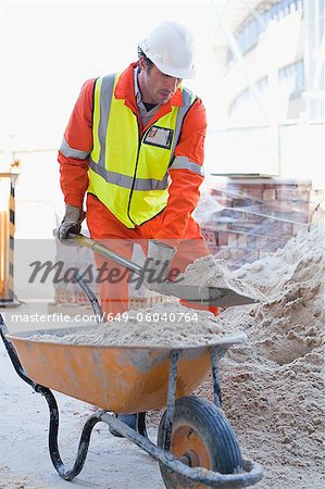 Worker shoveling concrete on site