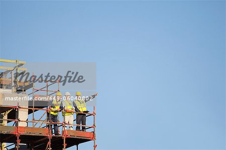 Workers standing on scaffolding on site