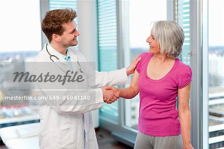 Arzt schüttelte Womans Hand im Büro