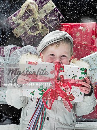 Boy holding Christmas present in snow