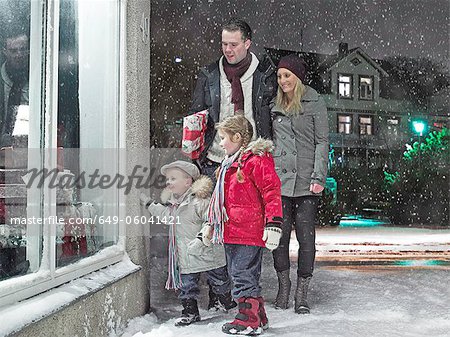 Family admiring Christmas window in snow