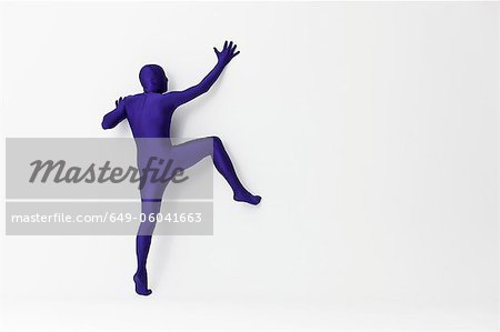 Man in bodysuit scaling wall