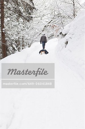 Man pulling sled in snowy field