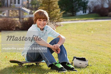 Garçon assis sur son skateboard dans un parc