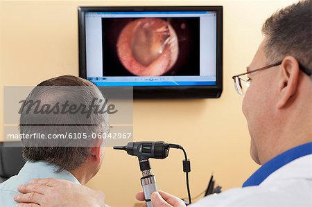 Audiologist doing live video inspection of ear canal while a patient watches on a computer screen