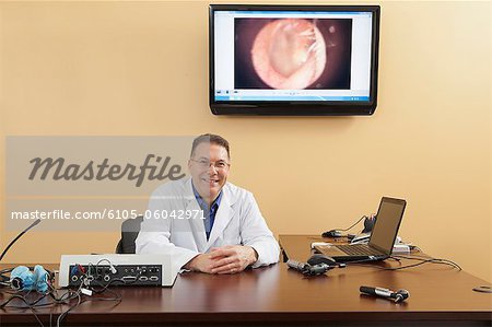 Portrait of an audiologist with his examination instruments and computer screen