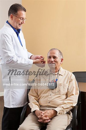 Audiologist inserting behind-the-ear hearing aid into a patient's ear during programming