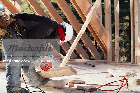 Carpenter cutting bevel on rafter with a circular saw