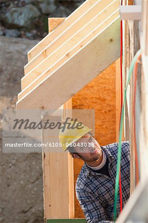 Carpenter reviewing exterior framing of a house