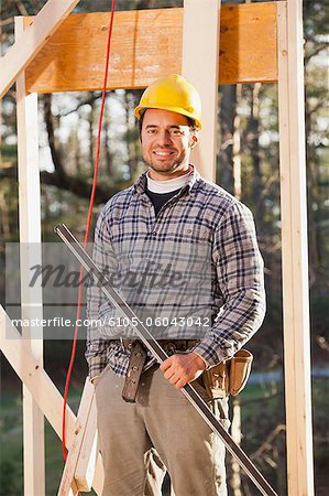 Portrait of a carpenter holding a level on house framing