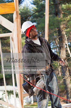 Carpenter with a nail gun reviewing work