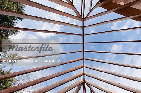 Low angle view of hip roof rafters viewed toward sky