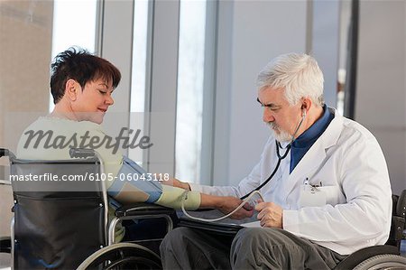 Arzt mit Muskeldystrophie im Rollstuhl, die Überprüfung der Blutdruck eines Patienten