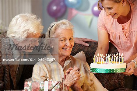 Daughter giving birthday cake to senior mother