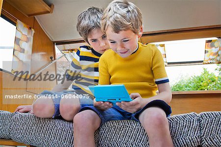 Two boys playing handheld video game