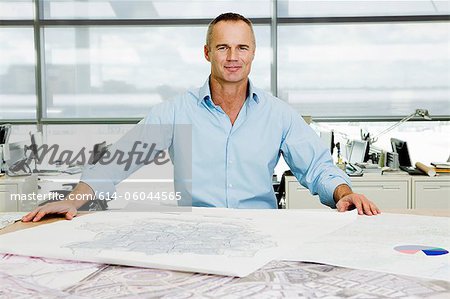 Portrait of an architect working on blueprints in office Portrait of an architect working on blueprints in office
