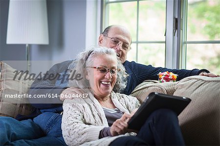Senior couple à l'aide de digital portable sur le canapé à la maison