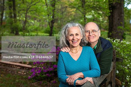 Senior couple sitting in forest, smiling, portrait