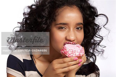 Jeune femme mangeant cupcake, studio shot