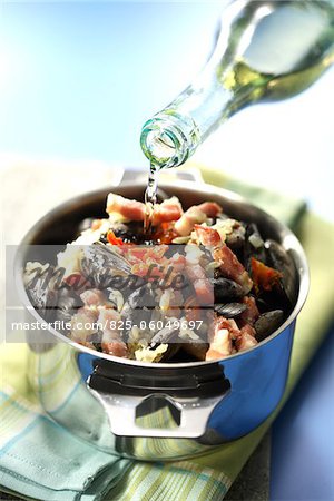 Pouring white wine over the mussels