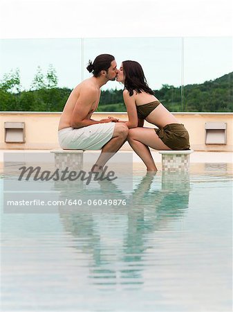 Italy, Tuscany, Couple kissing at swimming pool