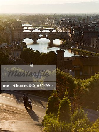 Italy, Florence, Couple with motorbike overlooking River Arno