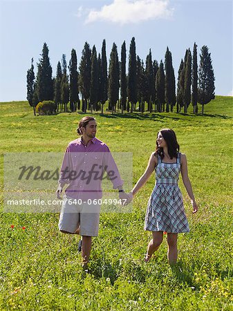 Italien, Toskana, Val D'Orcia, junges Paar, zu Fuß auf der Wiese