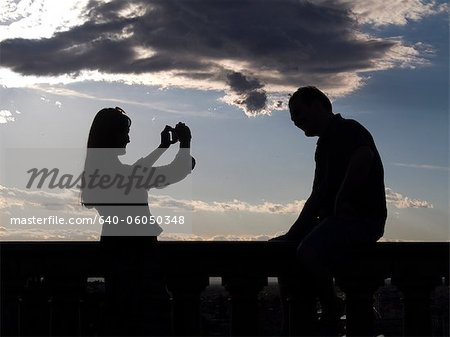 Italy, Florence, Silhouette of woman photographing man at sunset