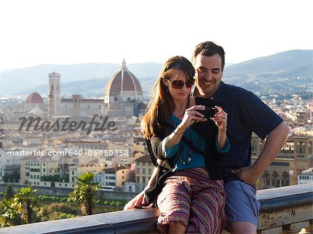 Italie, Florence, Couple à la recherche à l'appareil photo numérique, la physionomie d'une ville à l'arrière-plan