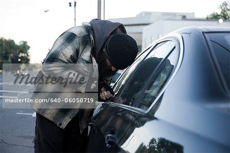 USA, Utah, Salt Lake City, Homeless man breaking into car, side view
