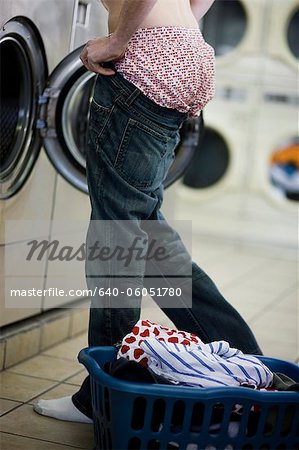 man putting on jeans at the laundromat
