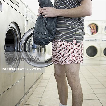 man taking off clothes at a laundromat