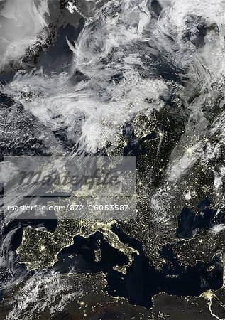Europe At Night With Cloud Coverage, True Colour Satellite Image. True colour satellite image of Europe at night with cloud coverage. This image in Lambert Conformal Conic projection was compiled from data acquired by LANDSAT 5 & 7 satellites.