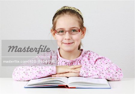 Cute schoolgirl with glasses reading book