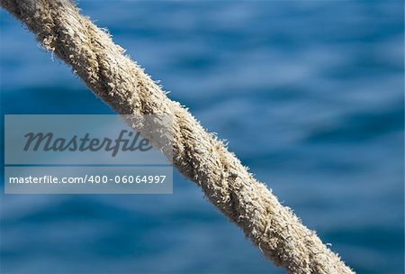 Stretched tight thick rope against blue sea water