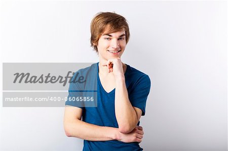 Portrait of a casual young man with a happy face, over a white wall
