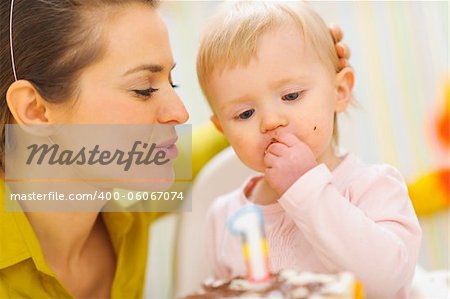 Mother congratulating eating first birthday cake baby
