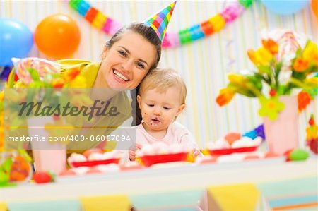 Smiling mom and eat smeared baby on birthday celebration party