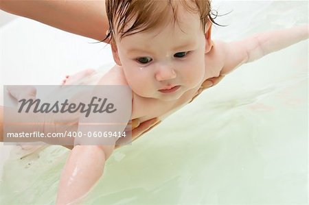 Infant holding with woman hands preparing to dive in bath