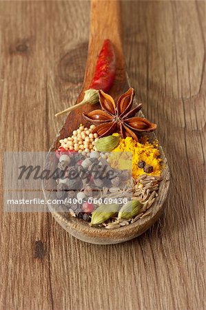 Colorful spices in a wooden spoon on the old table.
