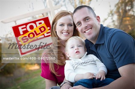 Happy Young Caucasian Family in Front of Sold Real Estate Sign.