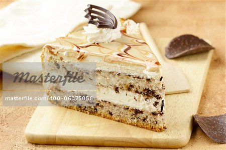 piece of cream  caramel cake with chocolate on a wooden board