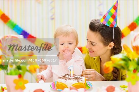 Portrait de l'heureuse maman et bébé mange le gâteau d'anniversaire