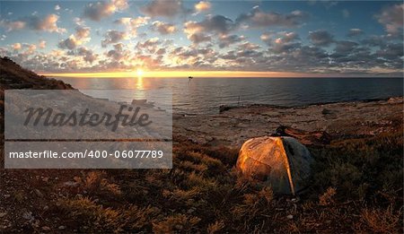 Beautiful seascape on sunrise with old boat on coast and clouds on background