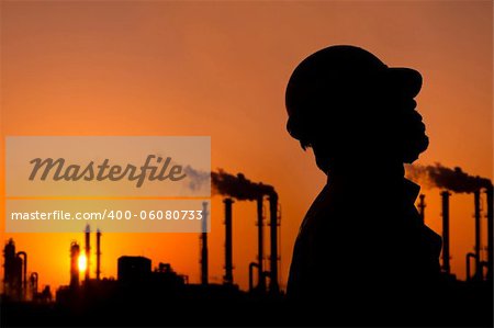 the silhouette of oil refinery worker at sunset