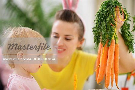 Mother showing baby bunch of carrots