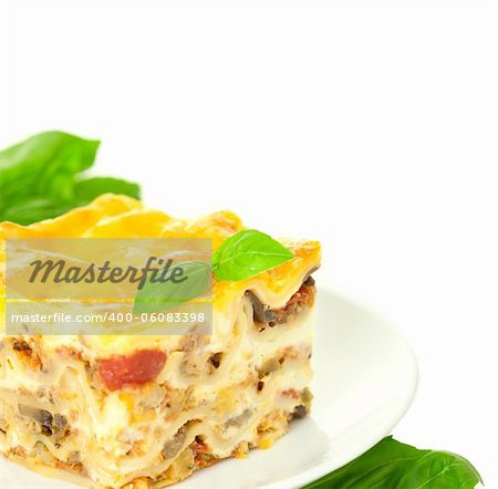 Portion of Classic Lasagna Bolognese with basil herb / isolated on white / corner composition